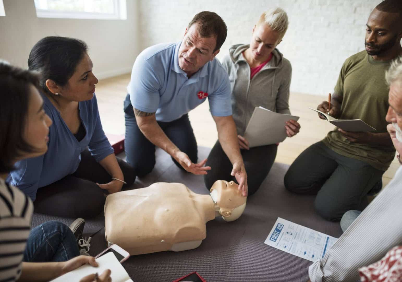 instructor delivering first aid CPR training to small group