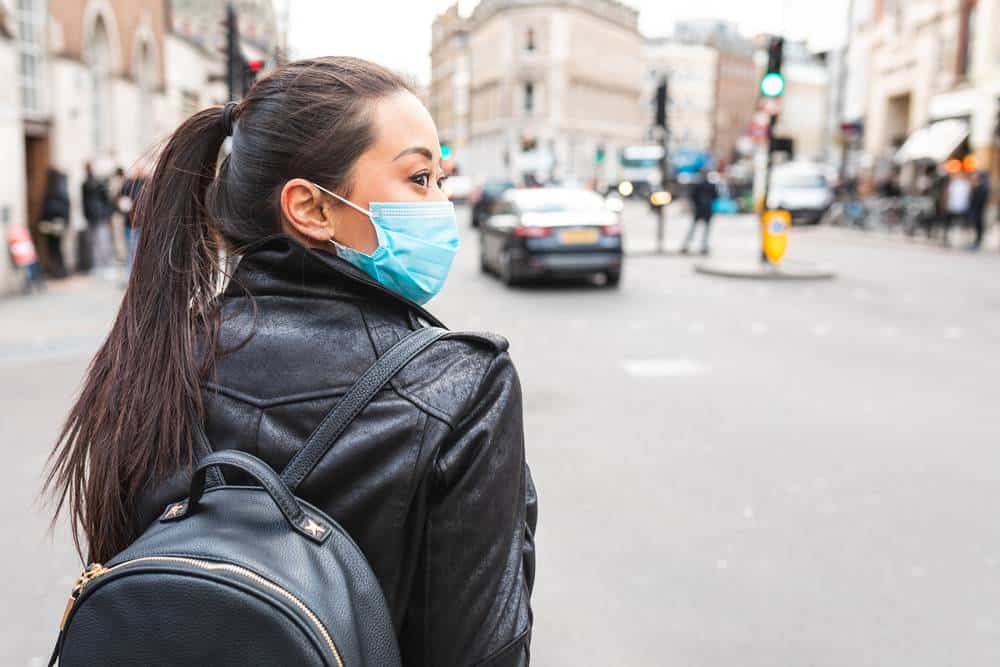 Chinese woman in London wearing anti coronavirus face mask while on essential travel during lockdown - health and lifestyle concepts
