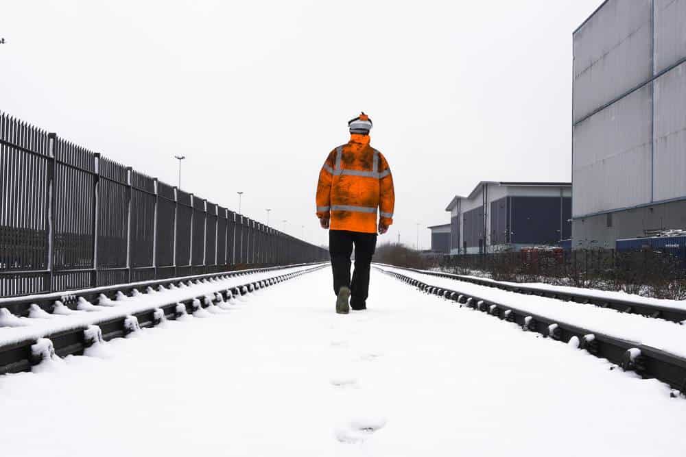 lone-construction-worker-walking-on-snow-and-train-tracks